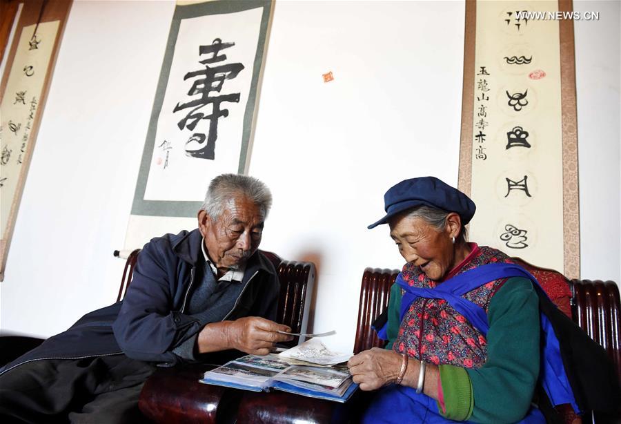 An elderly couple of local Naxi ethnic group browse through a family album at home in Tianhong Village, located at an altitude of around 3000 meters, in Yulong Naxi Autonomous County, southwest China's Yunnan Province, Nov. 24, 2015.