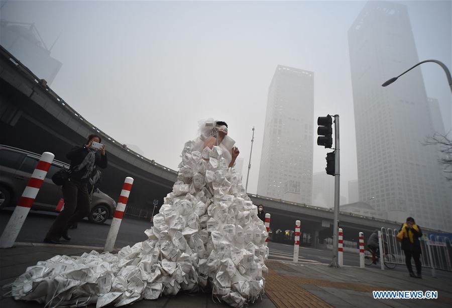 Artist Kong Ning wearing a wedding dress made up with 999 respirators walks on the street to call people's attention on environmental protection in Beijing, capital of China, Dec. 1, 2015. 