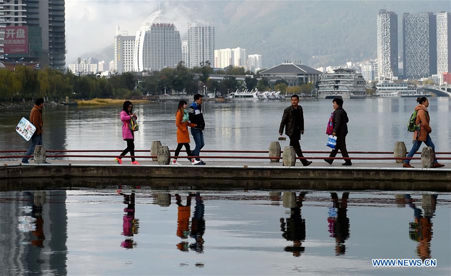 People stroll by the Erhai Lake in Dali Bai Autonomous Prefecture, southwest China's Yunnan Province, Dec. 9, 2015. 