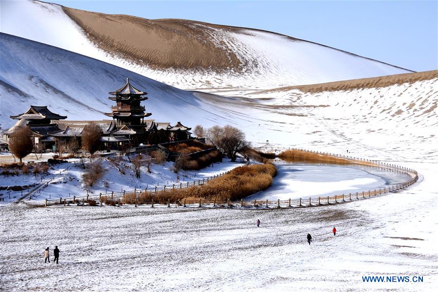 People visit the Crescent Lake scenery spot in Mingsha Mountain of Dunhuang City, northwest China's Gansu Province, Dec. 13, 2015.