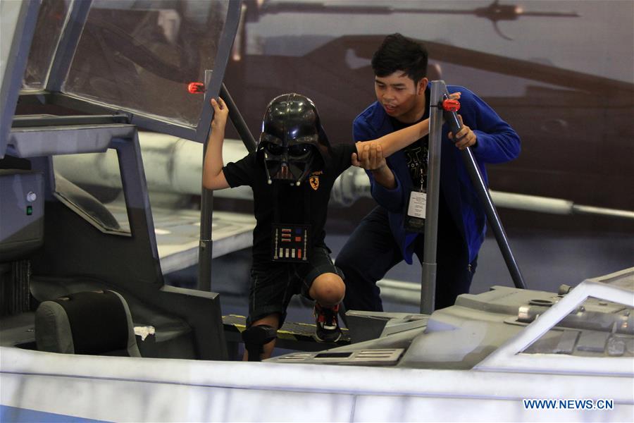 A boy wearing a Darth Vader helmet takes a seat inside the cockpit of a life-sized X-Wing Fighter during the premiere showing of the movie 'Star Wars: The Force Awakens' inside a mall in Pasay City, Philippines, Dec. 16, 2015.
