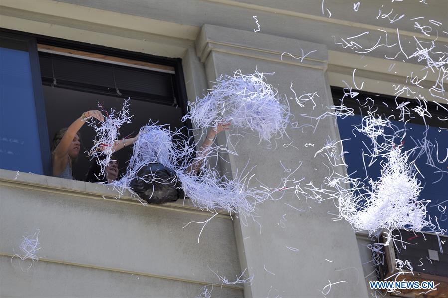 Employees toast from a window of a building, during the classical water fight and break of almanacs of end of year, in the New Year Eve, in the commercial and financial area of Ciudad Vieja in Montevideo, capital of Uruguay, Dec. 31, 2015. (Xinhua/Nicolas Celaya) 