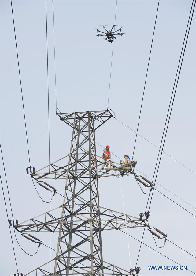 Workers check the transmission line with the help of a drone in Wuxi, east China's Jiangsu Province, Nov. 2, 2015.