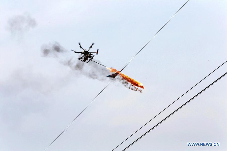 A drone burns off waste and sundries on the wire in Puyang, central China's Henan Province, March 17, 2015.