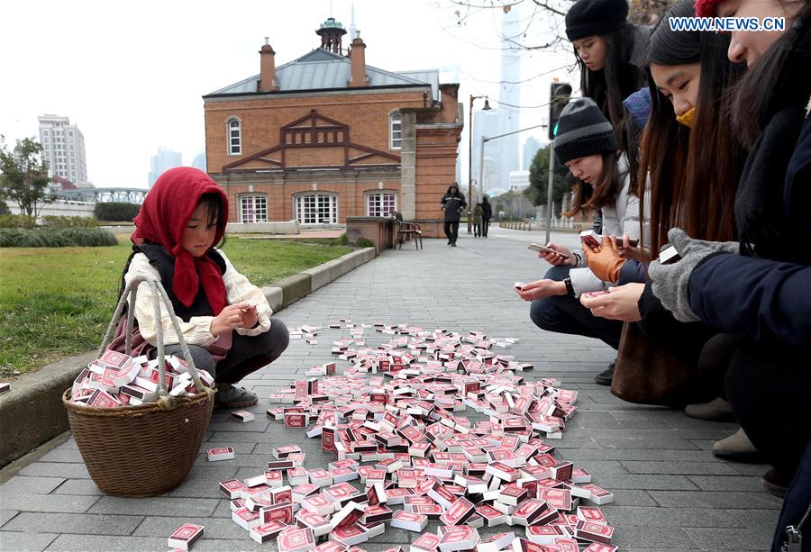 Passers-by scan QR code on the match box to donate new clothes at Waitan area in Shanghai, east China, Jan. 12, 2016. 