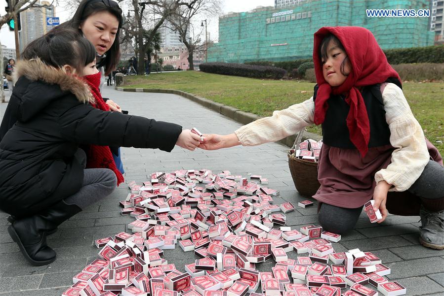 The 'little match girl' gives matches to a girl at Waitan area in Shanghai, east China, Jan. 12, 2016. 