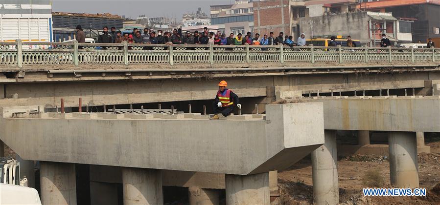  Nepalese people observe the ongoing process of placing concrete beams at the construction site of ongoing Ring Road expansion project assisted by China at Koteshwor, Kathmandu, Nepal, Jan. 14, 2016.