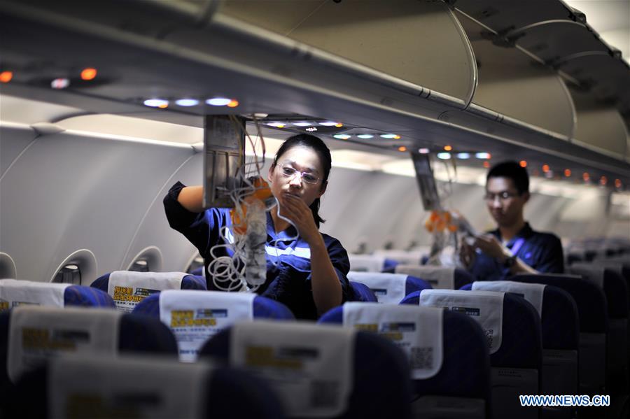 Staff members check oxygen masks inside a cabin at the maintenance base of China Southern Airlines in Haikou, capital of south China's Hainan Province, on Jan. 21, 2016.