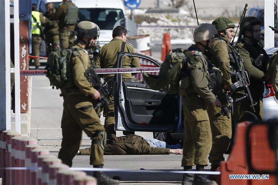 Israeli soldiers gather next to the body of Palestinian Amjad sokari who was shot dead after opening fire at Israeli soldiers in Beit Eil checkpoint north of the West Bank city of Ramallah, on Jan 31, 2016.