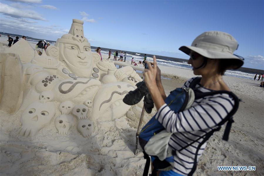 A woman takes a picture during the Third Latin American Meeting of Sand Sculptures in Marindia, Uruguay, on Jan. 31, 2016. 