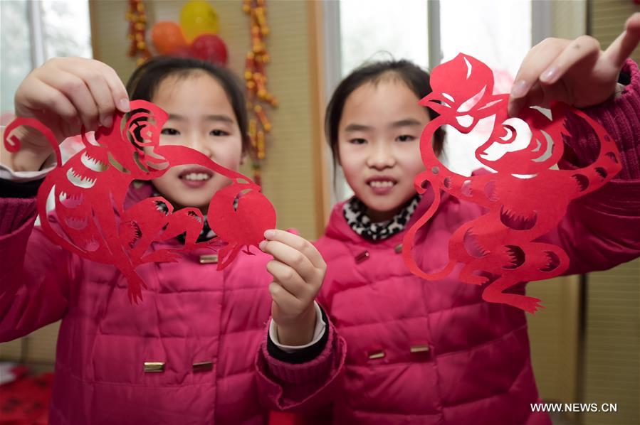 Zhu Bingqing (R) and her sister Zhu Bingjie show monkey-pattern paper-cutting works in a community of Hefei, east China's Anhui Province, Jan. 31, 2016, to greet the upcoming Spring Festival