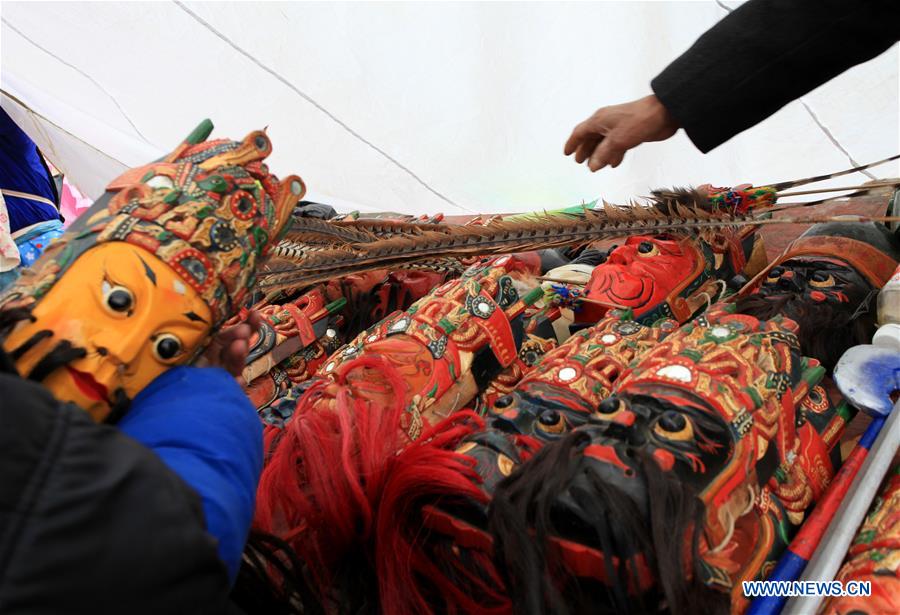 A performer prepares to take a mask to perform Gaotai Dixi, a local folk opera staged on the open space of flat land, at Weiqi Village of Puding County, southwest China's Guizhou Province, Feb. 15, 2016. 