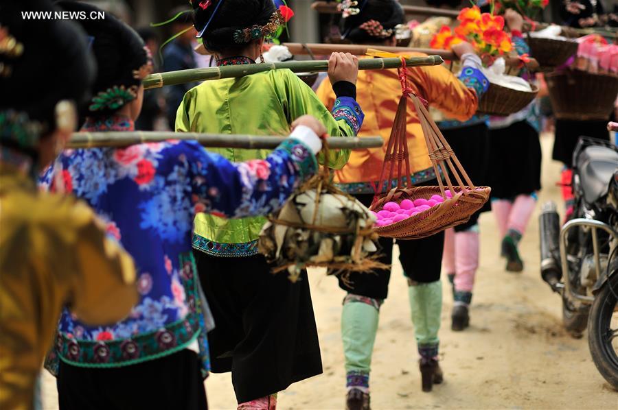 Women of Miao ethnic group carrying gifts on the shoulder walk at Ma'an Village of Congjiang County, Qiandongnan Miao and Dong Autonomous Prefecture, southwest China's Guizhou Province, Feb. 13, 2016. 