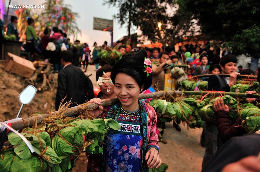 A woman of Miao ethnic group carrying meals on the shoulder walks at Ma'an Village of Congjiang County, Qiandongnan Miao and Dong Autonomous Prefecture, southwest China's Guizhou Province, Feb. 13, 2016. 