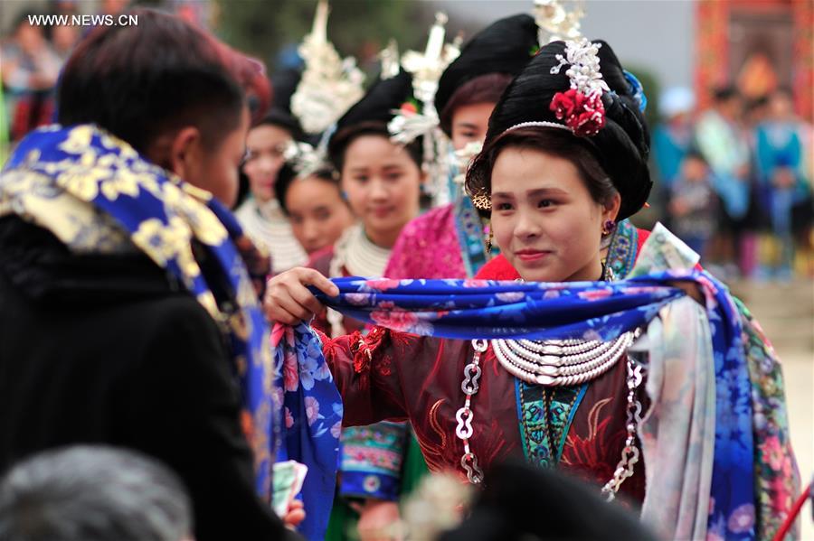 A woman of Miao ethnic group presents a scarf to a singer at a festival gathering to sing Miao songs at Ma'an Village of Congjiang County, Qiandongnan Miao and Dong Autonomous Prefecture, southwest China's Guizhou Province, Feb. 13, 2016.