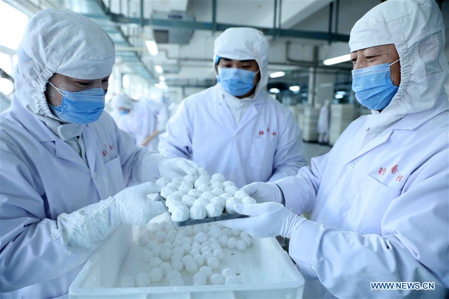 Cooks make Yuanxiao, glutinous rice flour dumpling with sweetened stuffing, at a workshop of Daoxiangcun, a time-honored foodstuff company, in Beijing, capital of China, Feb. 18, 2016.