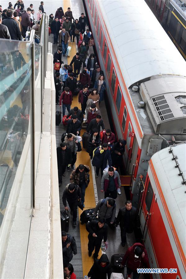 Passengers board a train at the railway station of Zhengzhou, capital of central China's Henan Province, Feb. 24, 2016. 