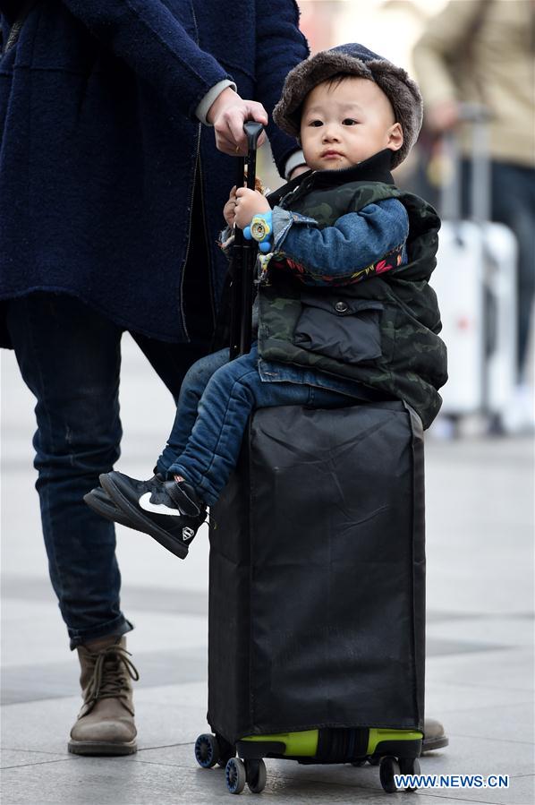 A boy sits on a suitcase at the railway station of Zhengzhou, capital of central China's Henan Province, Feb. 24, 2016.