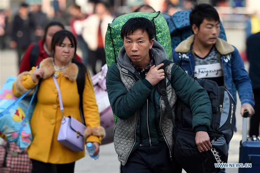 Passengers carrying their luggage walk towards the railway station of Zhengzhou, capital of central China's Henan Province, Feb. 24, 2016.