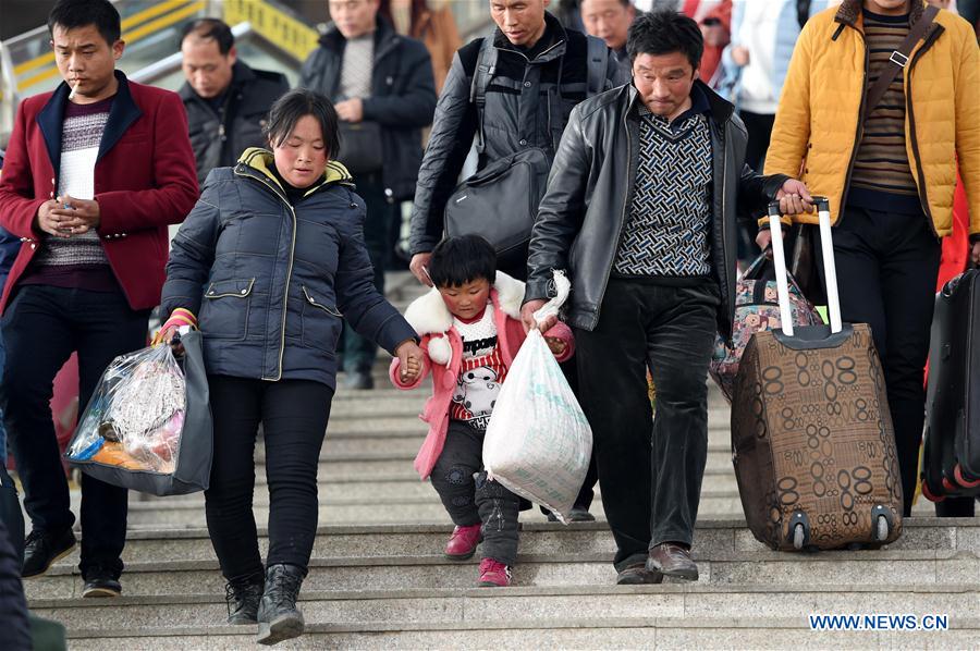 Passengers carrying their luggage walk towards the railway station of Zhengzhou, capital of central China's Henan Province, Feb. 24, 2016.