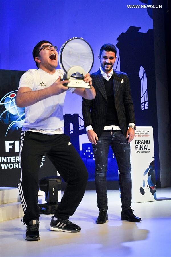 Mohamad Al-Bacha(L) of Denmark lifts his champion trophy presented by David Villa during the Grand Final of FIFA Interactive World Cup 2016 in New York, the United States, March 22, 2016.