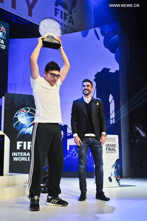 Mohamad Al-Bacha(L) of Denmark lifts his champion trophy presented by David Villa during the Grand Final of FIFA Interactive World Cup 2016 in New York, the United States, March 22, 2016. 