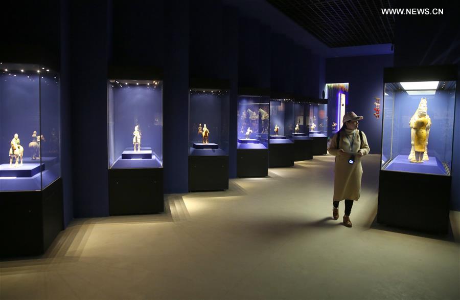 A visitor looks at a tri-colored glazed pottery work is seen displayed at an exhibition in Shaanxi History Museum in Xi'an, capital of northwest China's Shaanxi Province, March 23, 2016. 