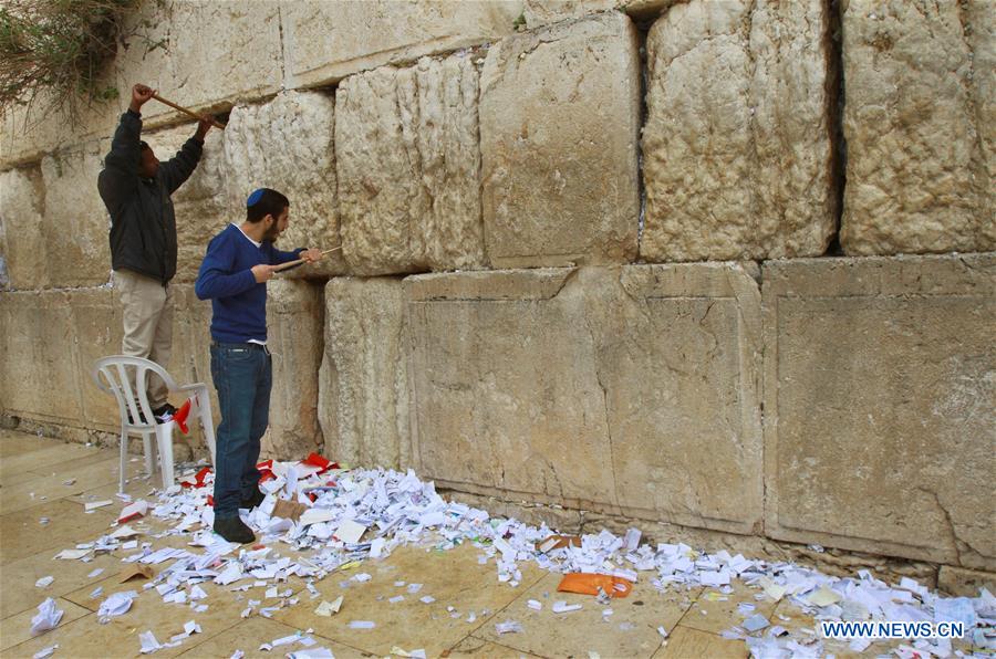 Employees remove thousands of handwritten notes placed between stones of the Western Wall, Judaism's holiest site in the Old City of Jerusalem, on April 12, 2016.