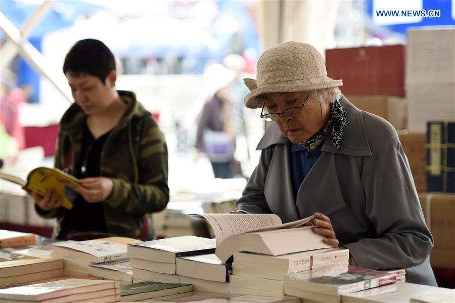 Women select books at a book fair in Chaoyang Park in Beijing, capital of China, April 15, 2016.