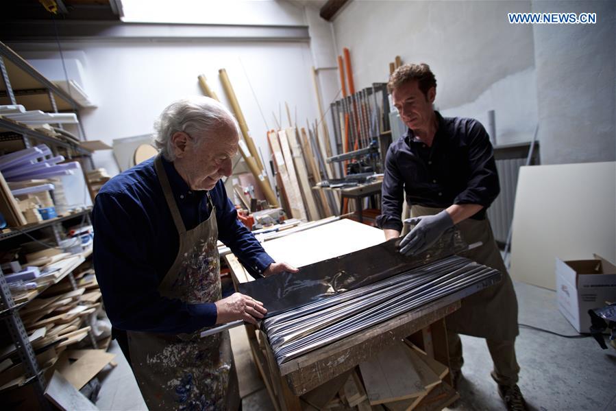 Mariani (L) and his assistant Fabio Ciaravino make a fold out of a lead sheet, with the help of a column stick at his studio in Milan, Italy, on April 13, 2016.