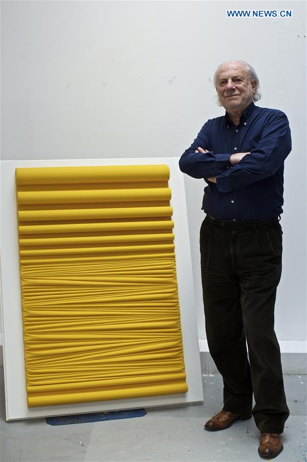 Mariani poses for a photo with one of his work at his studio in Milan, Italy, on April 13, 2016.