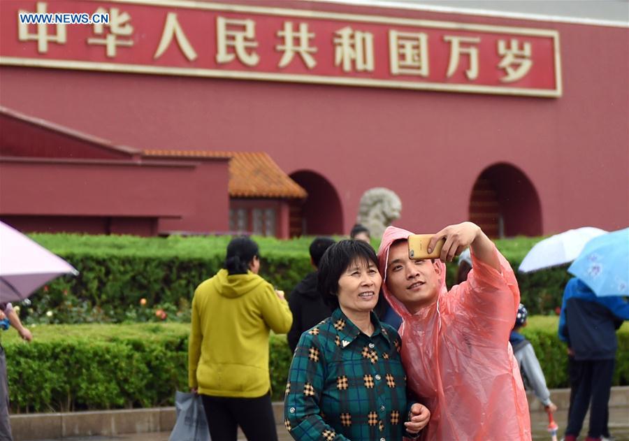 Tourists pose for a selfie in front of the Tian'anmen Rostrum on a rainy day in Beijing, capital of China, May 2, 2016.