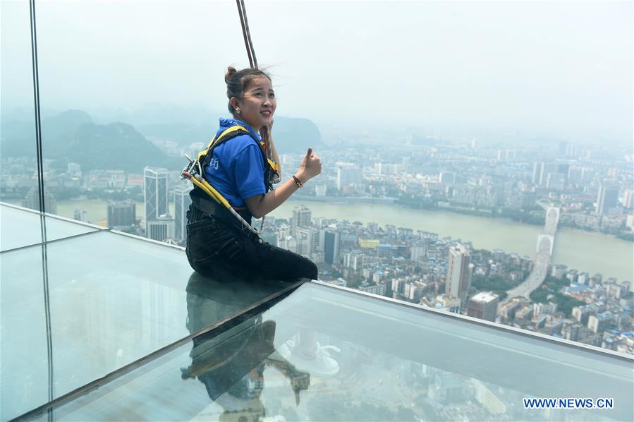 A tourist fastened by safty belt experiences sightseeing in the air on the Yunding glass-made plank road on a skyscraper in Liuzhou, south China's Guangxi Zhuang Autonomous Region, May 5, 2016. 