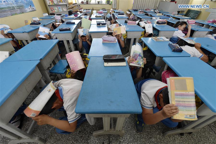 Students hide themselves under desks at the No. 3 primary school in Yongning County of northwest China's Ningxia Hui Autonomous Region, May 11, 2016.