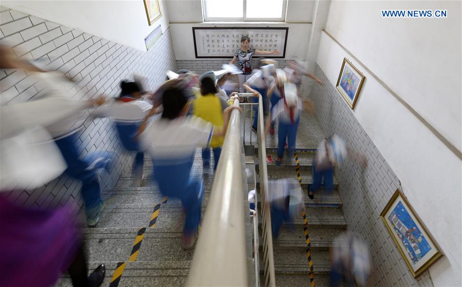 Students run under the guide of a teacher during an earthquake drill at the No. 3 primary school in Yongning County of northwest China's Ningxia Hui Autonomous Region, May 11, 2016. 