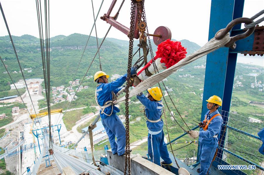 Workers install the last main cable backstay at the construction site of Fuma Yangtze River Bridge in Wanzhou of Chongqing, southwest China, May 30, 2016.