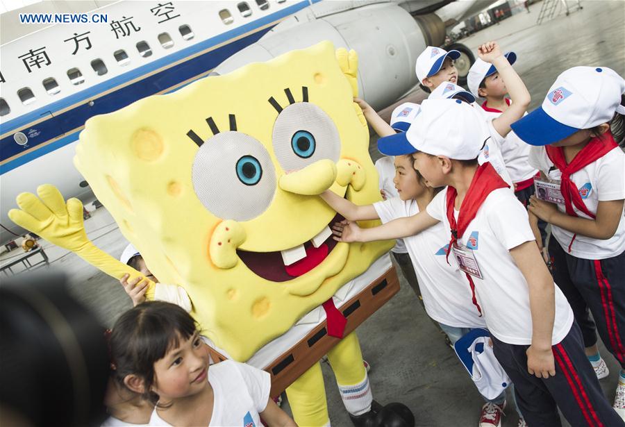 Children interact with a mascot inside a hangar during an aviation-themed visit in Wuhan, capital of central China's Hubei Province, May 30, 2016.