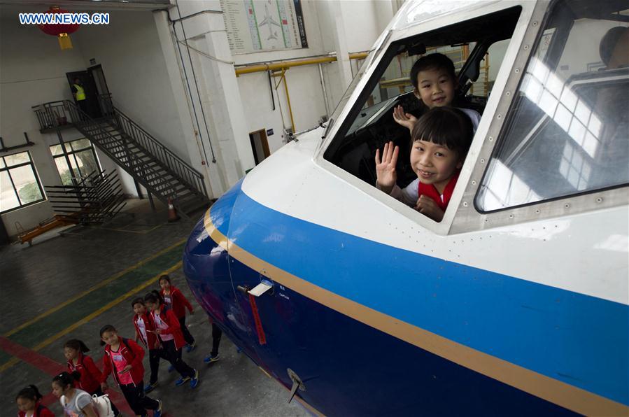 Two girls wave inside an airliner cockpit during an aviation-themed visit in Wuhan, capital of central China's Hubei Province, May 30, 2016. 