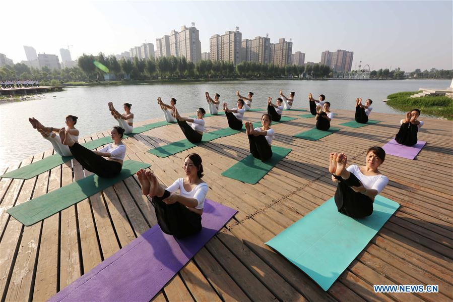 People practise yoga at the Longquan Lake Park in Wuzhi County of Jiaozuo, central China's Henan Province, June 18, 2016. 