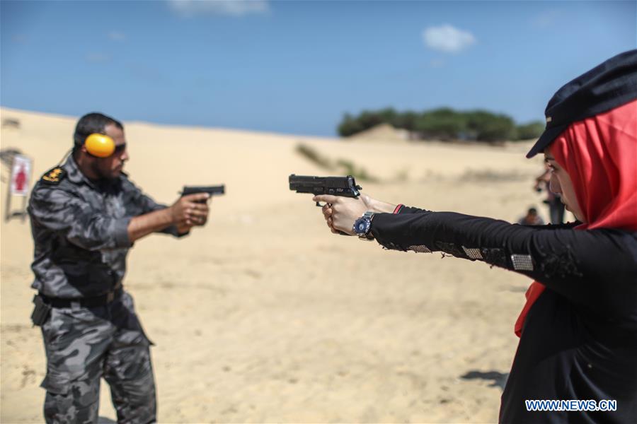 A Palestinian girl aims a pistol as she prepares to fire at a target during a training session for the families of Hamas officials, organized by Hamas-run Security and Protection Service, in Khan Younis in the southern Gaza Strip, July 24, 2016.