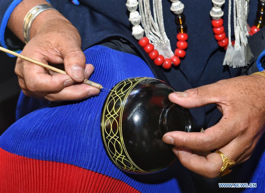 A folk artist paints on a lacquer during an intangible cultural heritage show of Liangshan Yi Autonomous Prefecture, in Xichang, southwest China's Sichuan Province, July 26, 2016. 