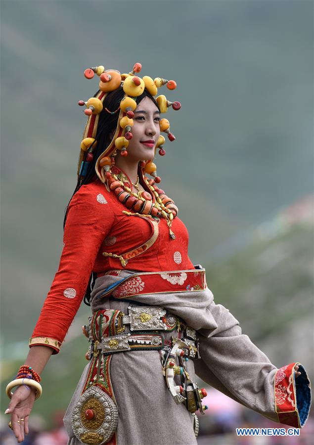 A model presents traditional Tibetan costumes during a fashion show held at Batang grassland of Yushu City of Yushu Tibetan Autonomous Prefecture, northwest China's Qinghai Province, July 26, 2016.