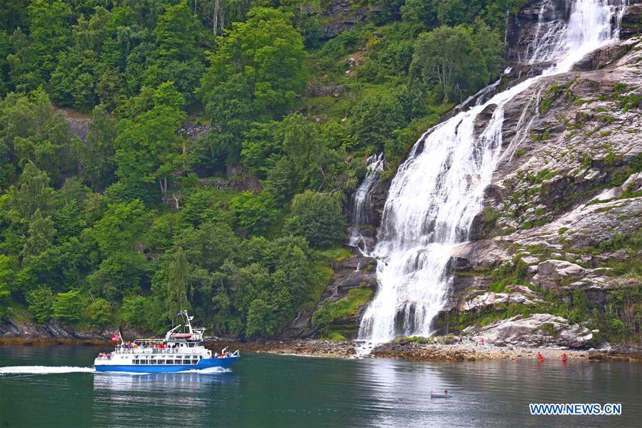 Tourists take a boat to appreciate a waterfall at Geirangerfjord in Norway, July 20, 2016.