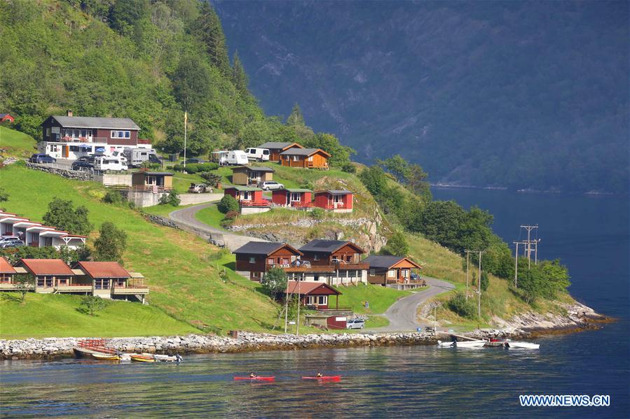 Tourists take a boat to appreciate a waterfall at Geirangerfjord in Norway, July 20, 2016.