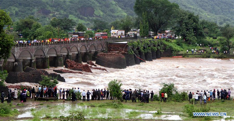 People watch the search operation in the flooded Savitri river after an old bridge collapsed due to torrential rain in Mahad, Indian state of Maharashtra, Aug. 3, 2016. 