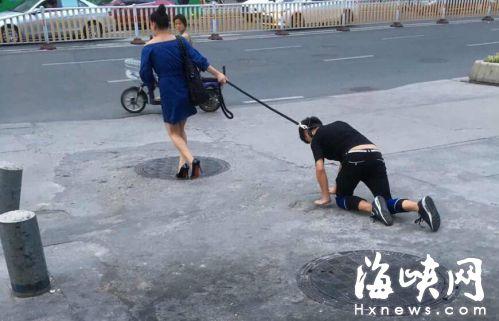 女子拉着男子在路上爬行(网友图)