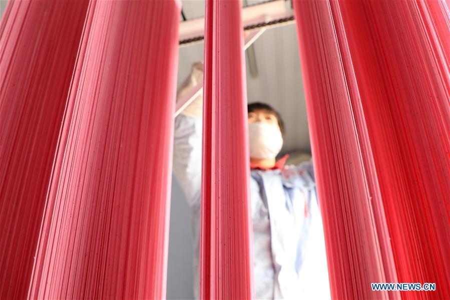 A staff member airs colored noodles at a workshop in Binzhou, east China\'s Shandong Province, Jan. 29, 2019. These noodles are naturally colored using vegetables or fruits such as carrot, spinach and dragon fruit. (Xinhua/Zhang Chunfeng)