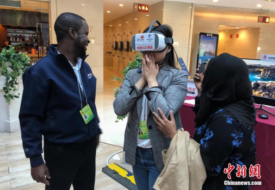 Mongolian journalist Enkhtur Anudari (M) experiences a 5G network device at the media center of the Two Sessions in Beijing\'s Media Center Hotel, March 11, 2019. (Photo: Cui Nan/China News Service)