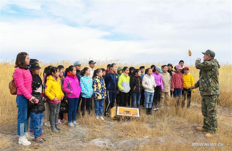 Shuanglong, a man of Mongolian ethnic group, explains knowledge on wildlife protection to primary students at the reeds along the Hulun Lake in the Hulun Buir City, north China\'s Inner Mongolia Autonomous Region, April 13, 2019. Shuanglong, a volunteer born in the 1980s, has been dedicated to protecting wildlife inhabiting along the Hulun Lake over the past ten years. Over 40 endangered animals have been saved through his efforts. Shuanglong has organized various activities including photo exhibitions and lectures, as a way to raise awareness of wildlife protection among the public. Affected by Shuanglong, some volunteers also joined him to protect wildlife along the Hulun Lake. (Xinhua/Peng Yuan)