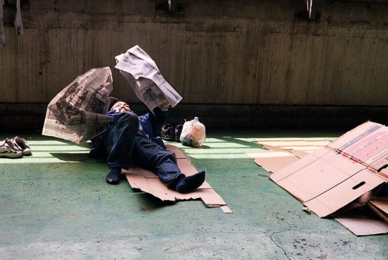 一名男子躺著读报,鞋子整齐地放在一边.